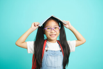 Portrait of happy lazy little girl covering head with book and smiling to camera.