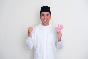 Fototapeta premium Asian moslem man holding paper money with excited gesture