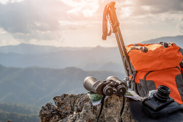 Backpack and binoculars and camera and stick on top rock mountain. Travel photos contributor concept.