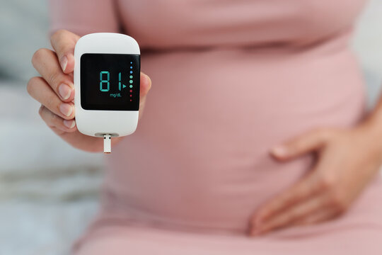 pregnant woman holding glucose meter with result of measurement sugar level. gestational diabetes concept.