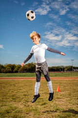 Child Boy Soccer Player Head Butting Soccer Ball on Soccer Field