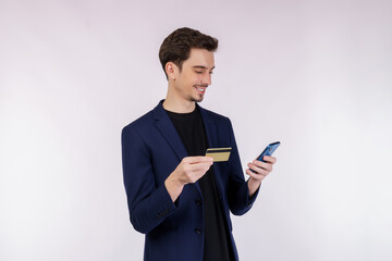 Portrait of happy young businessman standing using mobile cell phone and holding credit bank card isolated on white color background studio