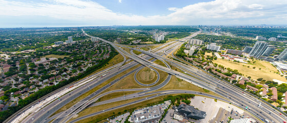 Fototapeta premium Top down aerial of cars drive across the expressway road in Canada. Cityscape and Highway. Transportation traffic at multilevel high speed road complex in North America.