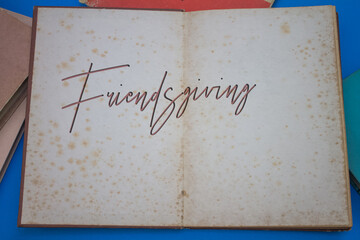 Friendsgiving word in opened book with vintage, natural patterns old antique paper design.