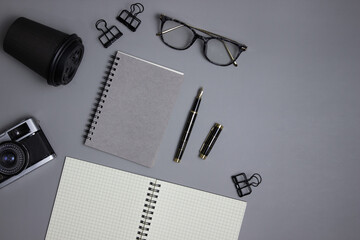 Office items with glasses, pen and notebooks over the grey background. 