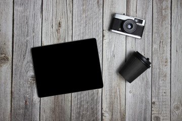 Tablet with camera and a cup of coffee over the wooden table. 