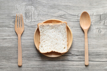 Whole wheat bread in the wooden bowl with spoon and fork on wooden background, Healthy Eating and Diet concept