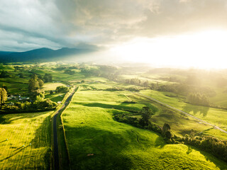 Sun bursting through clouds onto green farm land