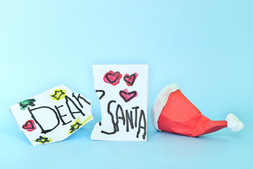 Torn Christmas letter to Santa Claus from kid beside a fallen Santa hat. Missing Santa, sad Christmas and wish not granted concept.