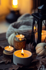 Cozy autumn composition with aromatic candle, pumpkins, wool sweater, leaves, cinnamon. Aromatherapy on a grey fall morning, home atmosphere of cosiness and relax. Wooden background close up.