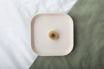 a yellow peeled matoa fruit on a white plastic plate
