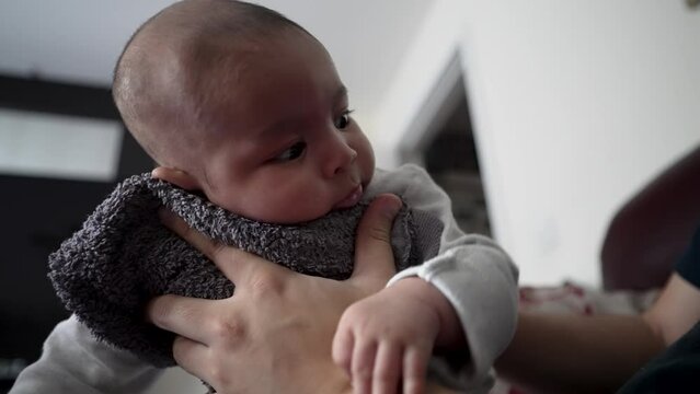 Father Using Towel To Gently Hold His 2 Month Old Son On The Front To Help Him Burp After Drinking Milk. Low Angle, Close Up, Slow Motion