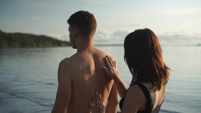 Woman touching man back, healing energy in palms, yoga couple training, sunny day on beach