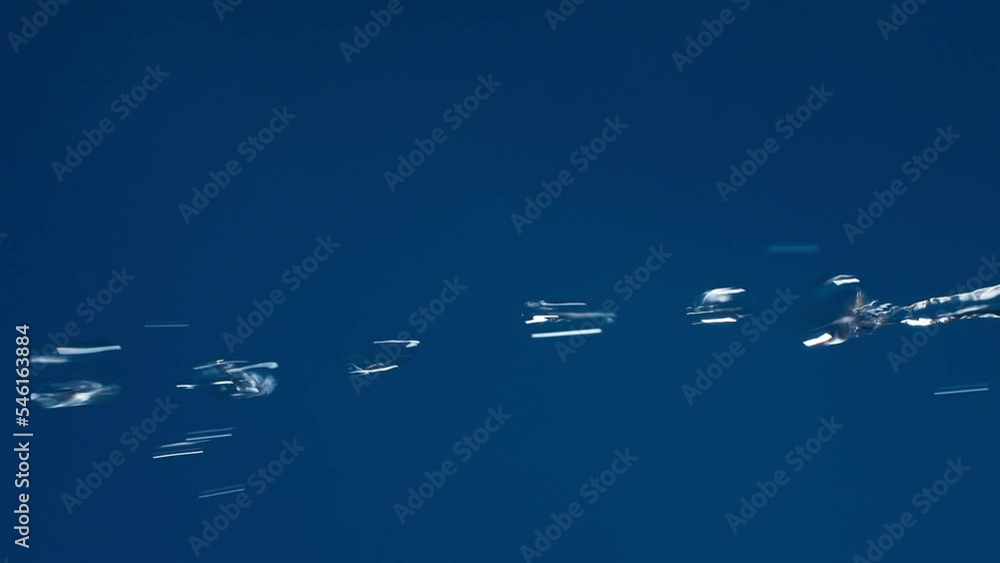 Poster vertical of real pure water flowing down with splashing on blue background shooting in slow motion