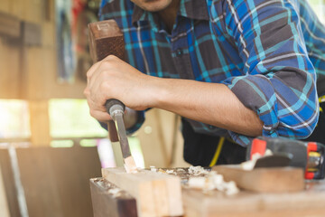 Carpentry professional, asian young man, male carpenter use machines or tool, shavings rugged on wood, timber in small shop. Woodwork, furniture making, construction industry. Owner small business.
