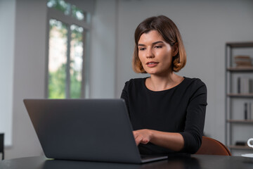 Satisfied attractive businesswoman in formal wear typing on laptop