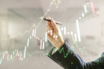 Man hand with pen working with abstract virtual financial graph on blurred office background, forex...