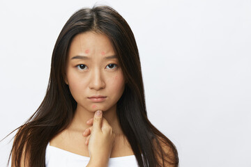 Fototapeta premium Asian woman hand signals, finger pointing facial skin problems, acne and inflammation, red rash and allergies, chicken pox, sadness from rashes. Facial skin care concept for diseases and nerves