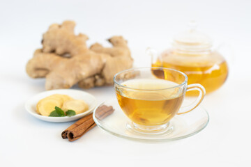 a cup of tea with ginger root, lime, cinnamon and teapot on white background. Health drink concept.