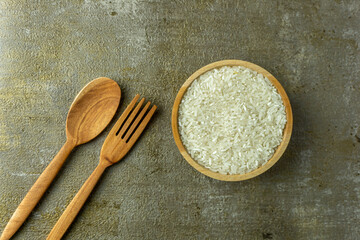 uncooked rice or dry rice. raw rice in wooden bowl with wooden spoon and fork