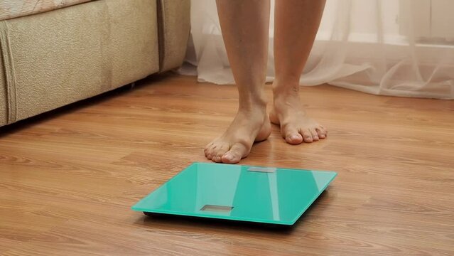 Women's legs go to the scales, stand on them to measure weight