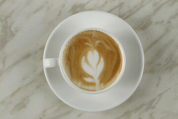 Top shot of coffee in a white cup with plant and heart foam art