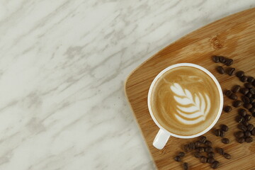 Top shot of coffee in a white cup with plant and heart foam art
