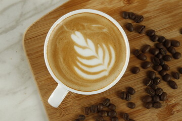 Top shot of coffee in a white cup with plant and heart foam art