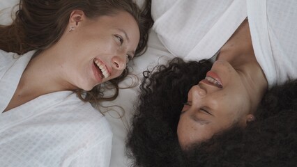 Obraz na płótnie Canvas Two female friends having smile with good feeling on white bed