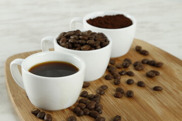 Three white cups with coffee, coffee beans and coffee grounds