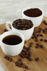 Three white cups with coffee, coffee beans and coffee grounds