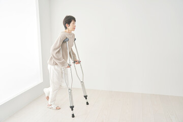 骨折して松葉杖を使って歩く女性