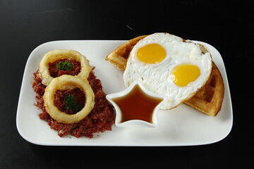 Corned beef hash breakfast with sunny side up eggs and waffles