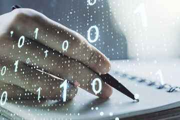 Double exposure of creative abstract binary code hologram and man hand writing in notebook on background. Database and programming concept