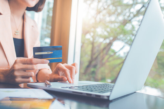 Woman holding credit cards and using laptops shopping online.