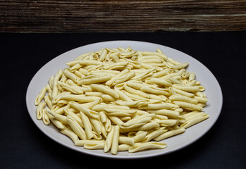 Uncooked Italian Maccheroni al pettine pasta on black background.