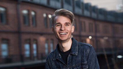 Portrait of a young and attractive Caucasian guy with a stylish hairstyle in a denim jacket.