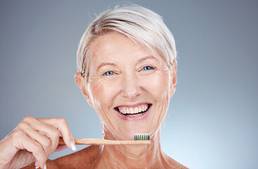 Portrait, senior woman and brushing teeth for dental hygiene, fresh breath and smile against grey studio background. Oral health, mature female and elderly lady with toothbrush and cleaning mouth.