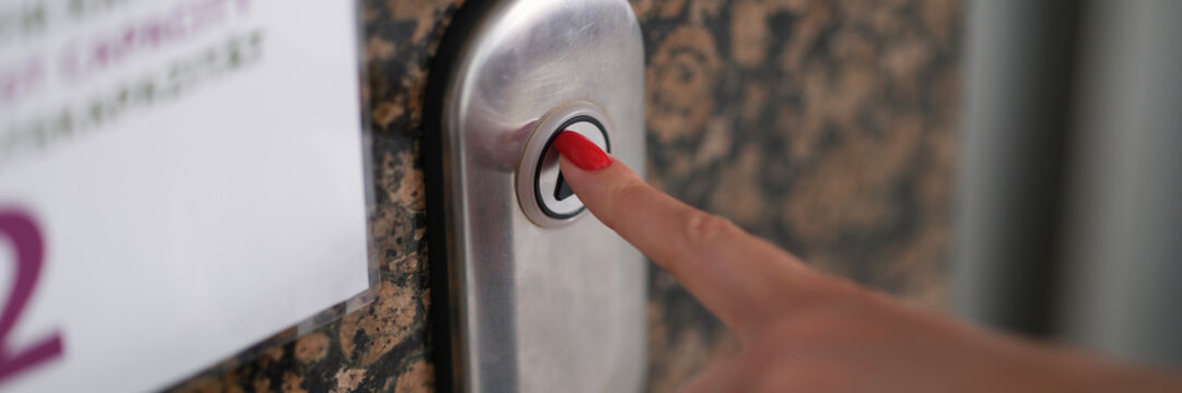 Female finger with red manicure pressing elevator button closeup