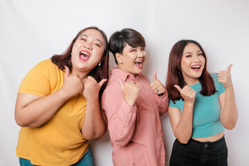 A portrait of three friends looks excited and gives thumbs up hand gesture of approval, isolated by a white background - obrazy, fototapety, plakaty