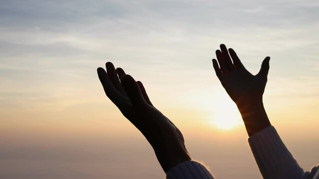 Silhouette of  man rise hand up on top of mountain and sunset sky abstract background. Freedom and travel adventure concept. pray or Praying, remembering God, Copy space .