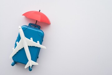 Travel insurance business concept. Red umbrella cover airplane and suitcase travelers on white...
