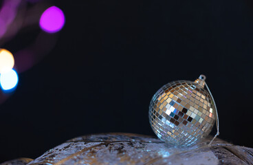 Silver disco mirror ball Christmas bauble close up with selective focus against black background....