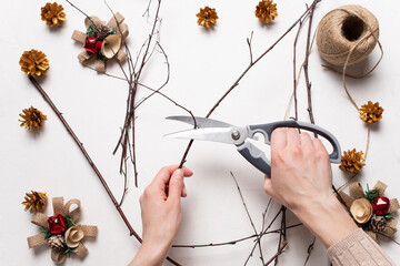 Women's hands decorate a homemade New Year's wreath. Eco-friendly christmas gift theme. whip, wreath without green branches. Step-by-step instruction. Do it yourself. Step 2. © Nikolay Kravchenko
