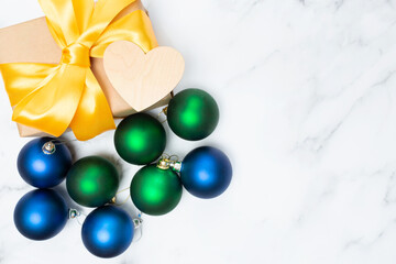 Beautiful gift box, an empty wooden heart and a lot of Christmas balls. Place for text. Copy space. Top view. Marble background. Flat lay.