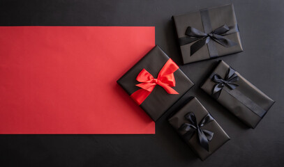 Gift box wrapped in red and black paper with a bow. Red, black background. Holiday concept. Place for text or advertising. Christmas. Valentine's Day.