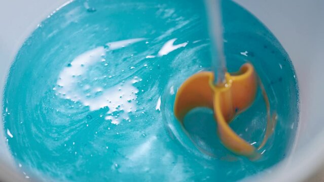 The process of preparing a multi-component epoxy resin. A professional kneads the resin with a colored tint