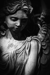 Black and white vertical image of sad angel of death. Fragment of an ancient statue.