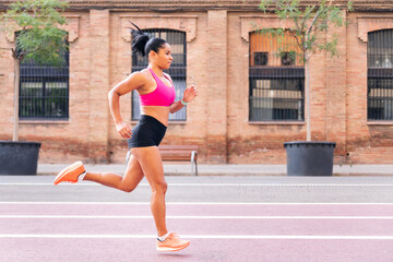 female athlete running on the city's athletics track during her workout, urban sport and healthy lifestyle concept, copy space for text