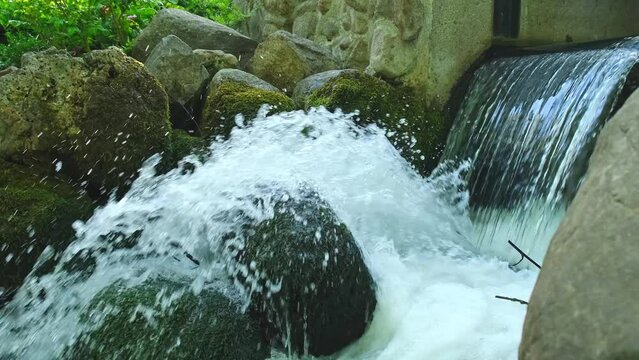 Waterfall cascade in Olivia public park Gdansk Poland. River waterfall falls from cliff and trees. Tourist attraction with small waterfall and clear water Unity with nature
